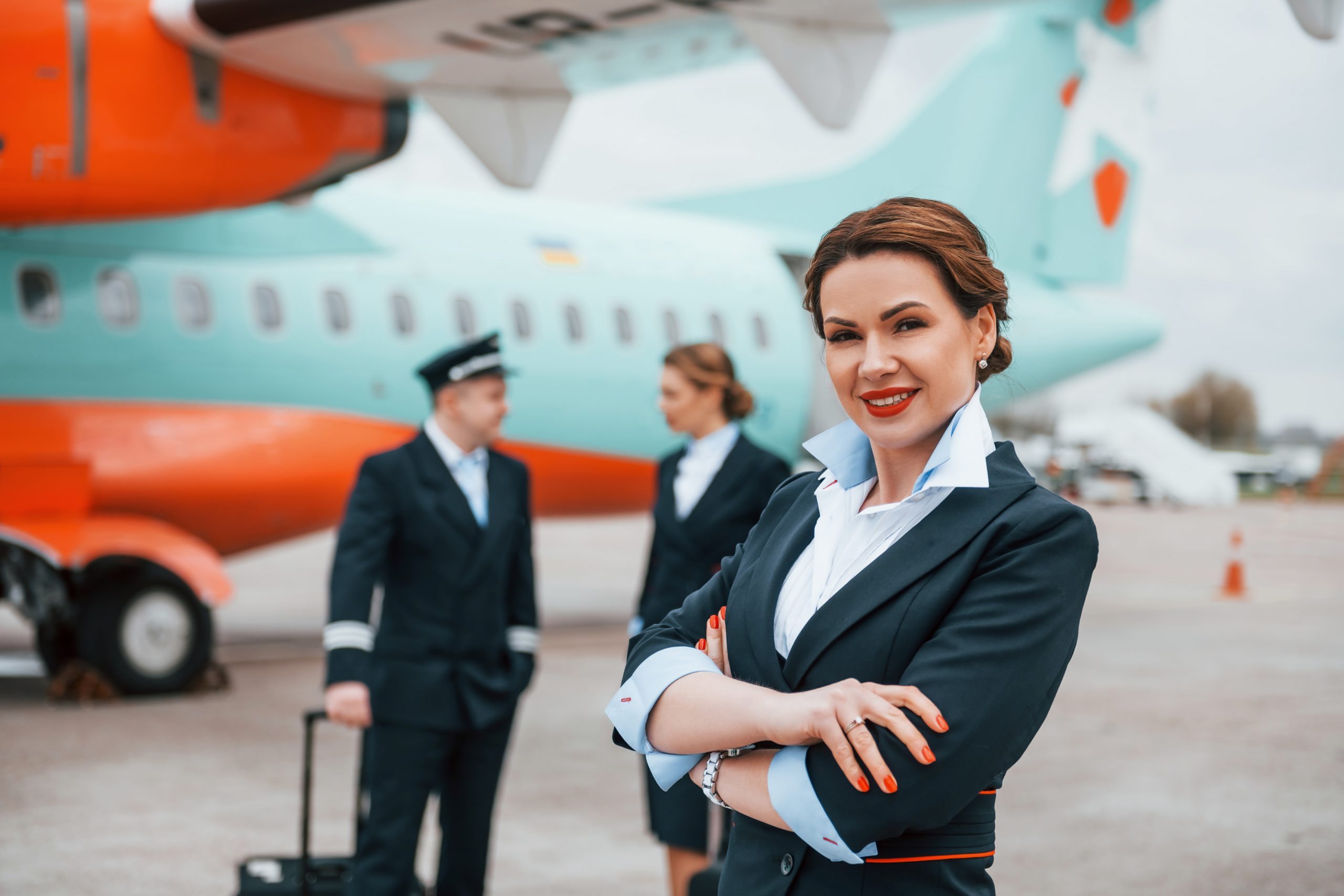 With luggage. Aircraft crew in work uniform is together outdoors near plane.