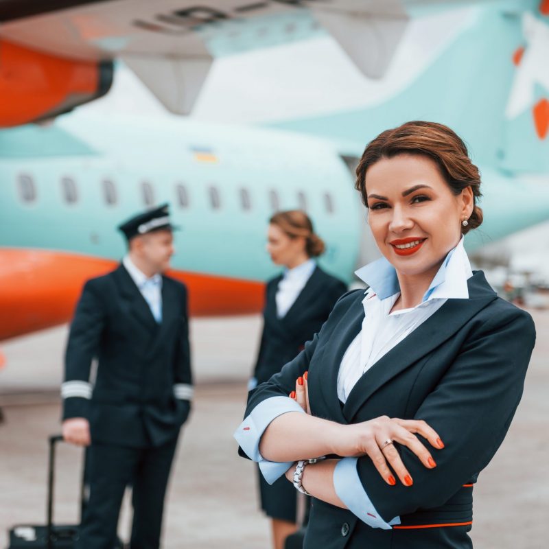 With luggage. Aircraft crew in work uniform is together outdoors near plane.